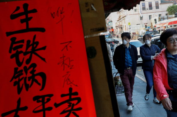 FILE PHOTO: People wear face masks walking through the Chinatown section of San Francisco, California, U.S., February 25, 2020.   REUTERS/Shannon Stapleton/File Photo