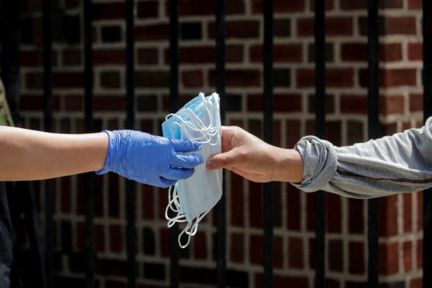 FILE PHOTO: A woman receives protective face masks while she waits in line at a food bank at St. Bartholomew Church, during the outbreak of the coronavirus disease (COVID-19) in the Elmhurst section of Queens, New York City, New York, U.S., May 15, 2020. REUTERS/Brendan McDermid