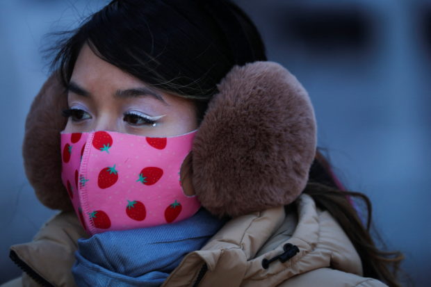 A woman wears a protective face mask and thick ear muffs during very cold temperatures in Manhattan in New York City, New York, U.S., January 26, 2022. REUTERS/Mike Segar