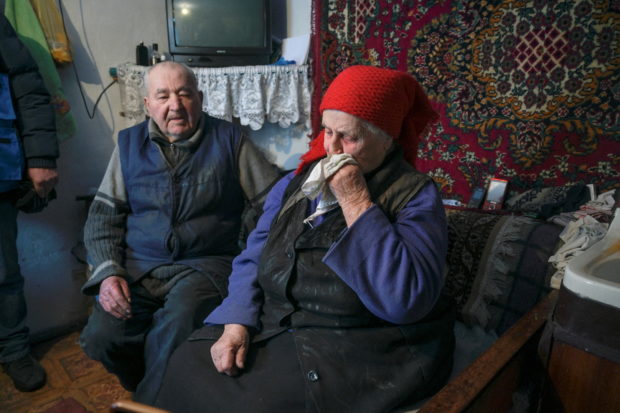 Local residents Kateryna and Dmytro sit on a couch as volunteers of a humanitarian mission visit their house in the settlement of Nevelske, located near the line of separation between the armed forces of Ukraine and pro-Russian rebels in the Donetsk region, Ukraine January 28, 2022. After a long life together Kateryna and Dmytro are among few people, who stayed in the deserted village following a destructive artillery attack in November 2021, still live in their house but face difficulties with energy and water supplies. REUTERS/Maksim Levin