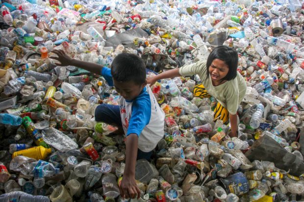 In this file photo taken on February 11, 2022 children play in piles of plastic wastes collected for recycling in Makassar. - The torrent of man-made chemical and plastic waste worldwide has massively exceeded limits safe for humanity or the planet, and production caps are urgently needed, scientists have concluded for the first time. (Photo by ANDRI SAPUTRA / AFP)