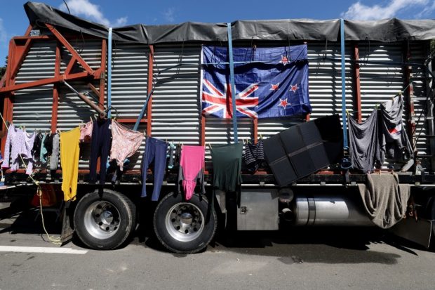 Laundry is hung to dry on the side of a farm truck adorned with a New Zealand flag hung upside-down by demonstrators, representing a nation in distress, on the ninth day of demonstrations against Covid-19 restrictions in Wellington on February 16, 2022, inspired by a similar demonstration in Canada. (Photo by Marty MELVILLE / AFP)