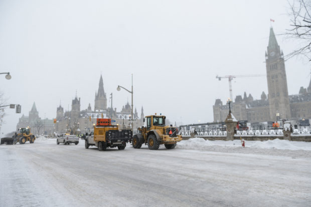 Police and city employees clean up Wellington Street in front of Parliament Hill, previously occupied by the Freedom Convoy, in Ottawa, Ontario, Canada, on February 20, 2022. - The last big rigs were being towed Sunday out of Canada's capital, where the streets were quiet for the first time in three weeks after a massive police operation ended a drawn-out siege over Covid health rules. (Photo by Andrej Ivanov / AFP)