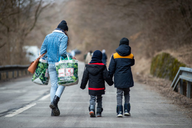 A woman with two children and carrying bags walk on a street to leave Ukraine after crossing the Slovak-Ukrainian border in Ubla, eastern Slovakia, close to the Ukrainian city of Welykyj Beresnyj, on February 25, 2022, following Russia's invasion of the Ukraine. - Ukrainian citizens have started to flee the conflict in their country one day after Russia launched a military attack on neighbouring Ukraine. (Photo by PETER LAZAR / AFP)