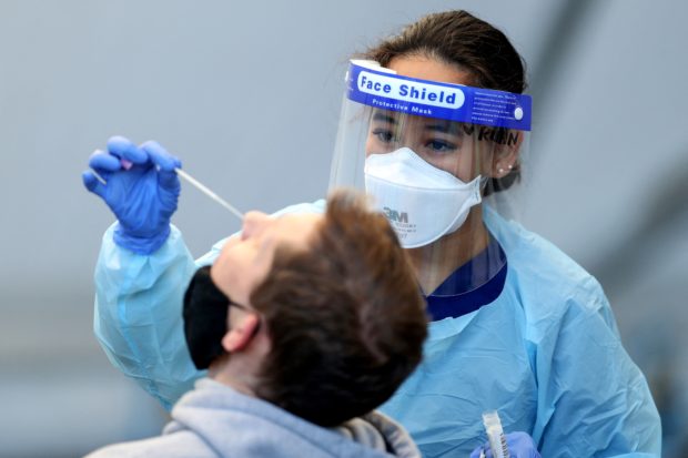A nurse wearing protective gear conducts a Covid test at Rushcutters Bay, an eastern suburb of Sydney, on July 13, 2021, during a lockdown as authorities stepped up efforts to curb a fast-growing coronavirus outbreak. (Photo by Brendon THORNE / AFP)
