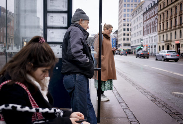 Commuters wait at a bus stop in Copenhagen on February 1, 2022, as Denmark becomes the first EU country to lift coronavirus restrictions despite record case numbers, citing its high vaccination rates and the lesser severity of Omicron variant. - February 1, 2022 de facto lifts all domestic restrictions, including the use of a vaccine pass, mask-wearing and early closings for bars and restaurants. Some border measures will remain in place for another four weeks, including tests and/or quarantine depending on travellers' immunity status. (Photo by Liselotte Sabroe / Ritzau Scanpix / AFP) / Denmark OUT