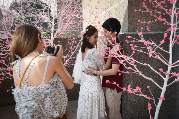 A newlywed couple poses for photos on Valentine's Day at the central post office in the Bang Rak, or "Love Village", district in Bangkok on February 14, 2018. (Photo by LILLIAN SUWANRUMPHA / AFP)