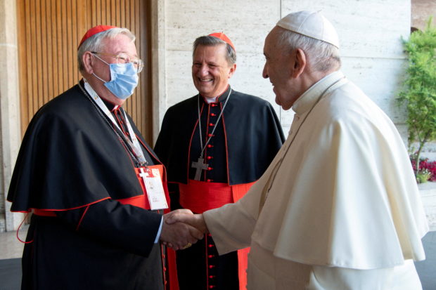 Cardinal Jean-Claude Hollerich S.J., Archbishop of Luxembourg, (in mask) greets Pope Francis at the opening of the Synodal Path at the Vatican October 9, 2021. Vatican Media/­Handout via REUTERS