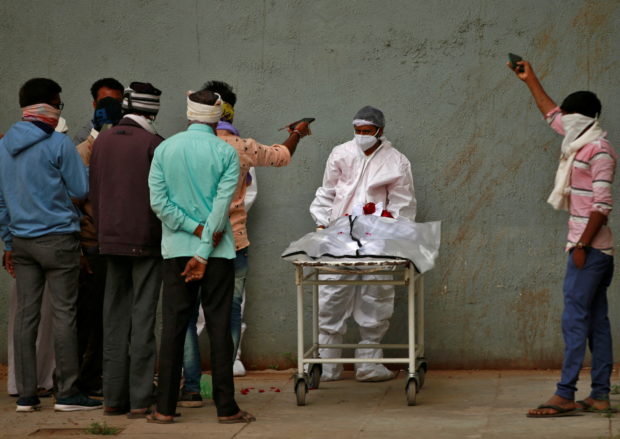 FILE PHOTO: Men take photographs of the body of their relative after he died from the coronavirus disease (COVID-19) at a hospital in Ahmedabad, India, January 24, 2022. REUTERS/Amit Dave