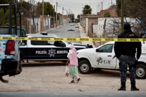 A woman walks at a crime scene where unknown assailants left the bodies of men wrapped in blankets in Fresnillo, Zacatecas state, Mexico February 5, 2022. REUTERS/Edgar Chavez