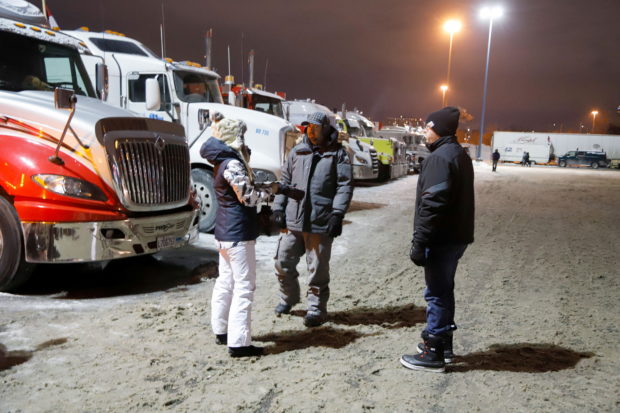 People stand in a staging area east of downtown after police raided the truckers' stockpile of fuel, as truckers and their supporters continue to protest against coronavirus disease (COVID-19) vaccine mandates, in Ottawa, Ontario, Canada, February 6, 2022. REUTERS/Patrick Doyle