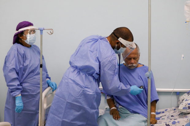 A doctor with Doctors Without Borders (MSF) attends to Marco Vargas, a patient who has the coronavirus disease (COVID-19), at a hospital where the organization is helping address mental health challenges faced by patients with the disease, in Caracas, Venezuela February 1, 2022. REUTERS/Leonardo Fernandez Viloria