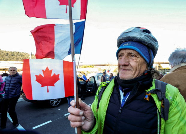 A French activist holds a Canadian flag before the start of their "Convoi de la liberte" (The Freedom Convoy), a vehicular convoy protest converging on Paris to protest coronavirus disease (COVID-19) vaccine and restrictions in Nice, France, February 9, 2022. REUTERS/Eric Gaillard REFILE - QUALITY REPEAT
