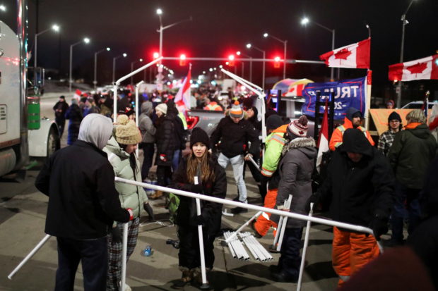 People erect a tent as truck drivers and supporters continue to block access to the Ambassador Bridge, which links Detroit and Windsor, in protest against coronavirus disease (COVID-19) vaccine mandates, in Windsor, Ontario, Canada February 10, 2022. REUTERS/ Carlos Osorio