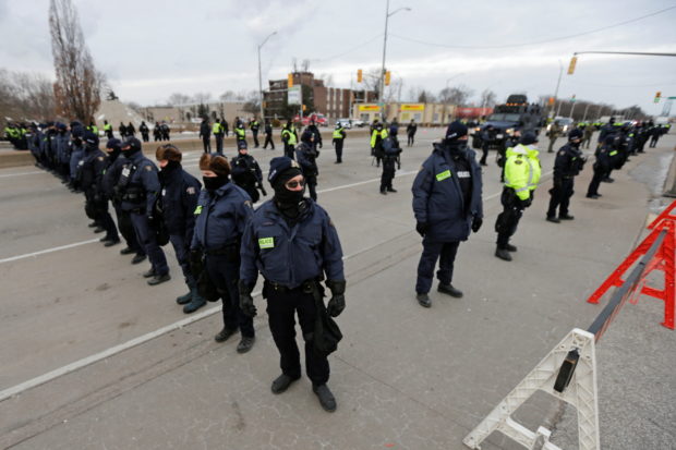 Police officers hold a line, on the road leading to the Ambassador Bridge, which connects Detroit and Windsor, after clearing demonstrators, during a protest against coronavirus disease (COVID-19) vaccine mandates, in Windsor, Ontario, Canada February 13, 2022. REUTERS/Carlos Osorio