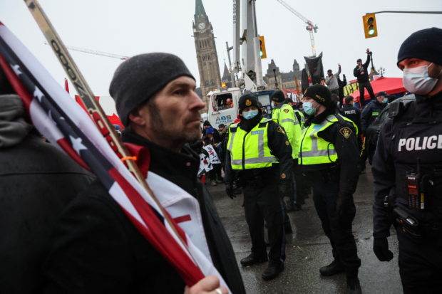 Police officers stand as other police detain a man who had been occupying a car around parked trucks and demonstrators, as protests against coronavirus disease (COVID-19) vaccine mandates continue, near the Parliament of Canada in Ottawa, Ontario, Canada, February 17, 2022. REUTERS/Shannon Stapleton