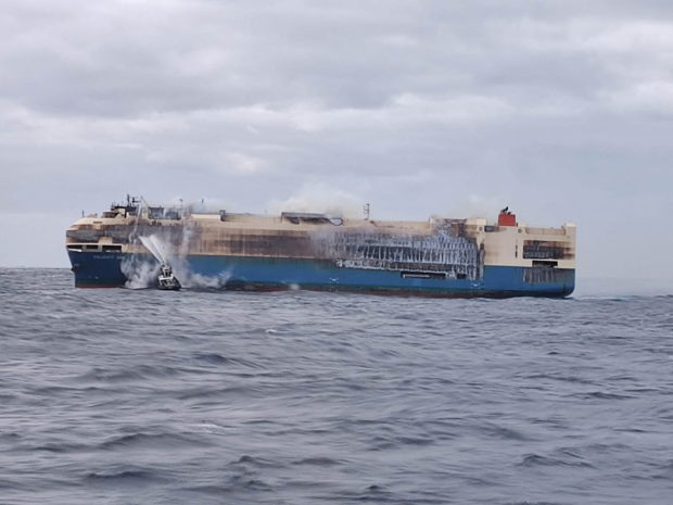 Tug boats spray water on blazing ship carrying Porsches and Bentleys near Azores