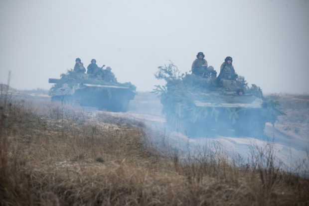 Ukrainian service members ride atop armoured fighting vehicles during tactical drills at a training ground in an unknown location in Ukraine, in this handout picture released February 22, 2022. Press service of the Ukrainian Armed Forces General Staff/Handout via REUTER