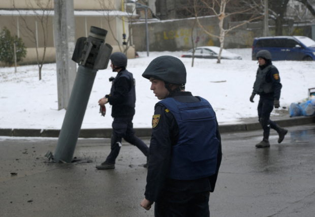 Members of the State Emergency Service of Ukraine walk towards a rocket case stuck on the driveway following recent shelling in Kharkiv, Ukraine February 25, 2022. REUTERS/Maksim Levin