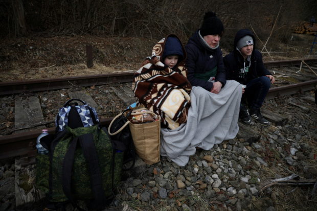 FILE PHOTO: People sit on the railway after crossing the border between Poland and Ukraine, after Russia launched a massive military operation against Ukraine, in Kroscienko, Poland February 27, 2022. REUTERS/Kacper Pempel/File Photo