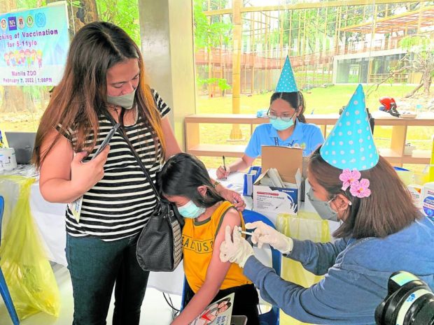 Photo of kid getting COVID-19 vaccination for story: Kids in Manila line up early to get COVID vaccine shots