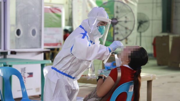 A health worker conducts a swab test on a woman in Navotas City. Image from Facebook/ Navoteño Ako-Navotas City PIO covid-19 cases ph covid-19 cases philippines recover