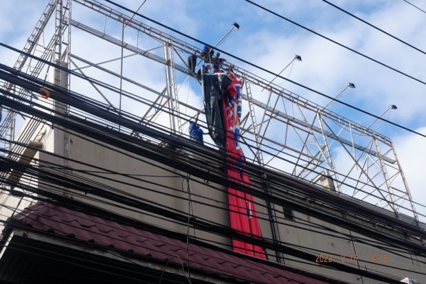 Personnel of Oplan Baklas take down an oversized billboard of a candidate. Image from Comelec / Facebook