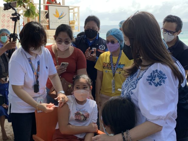 PHOTO: A child receives COVID-19 vaccination . Tourism chief Berna Romulo-Puyat consoles a child who is afraid of the vaccine. INQUIRERnet/John Eric Mendoza 
