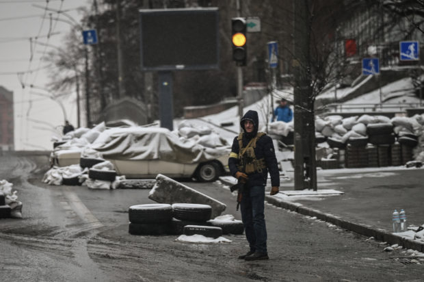 An armed man stands at a road block in downtown Kyiv