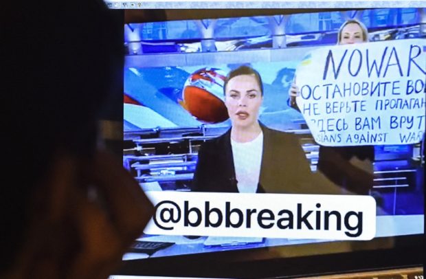 A man looks at a computer screen watching a dissenting Russian Channel One employee entering Ostankino on-air TV studio during Russia's most-watched evening news broadcast, holding up a poster which reads as "No War" and condemning Moscow's military action in Ukraine in Moscow on March 14, 2022 . - As a news anchor Yekaterina Andreyeva launched into an item about relations with Belarus, Marina Ovsyannikova, who wore a dark formal suit, burst into view, holding up a hand-written poster saying "No War" in English. (Photo by AFP)