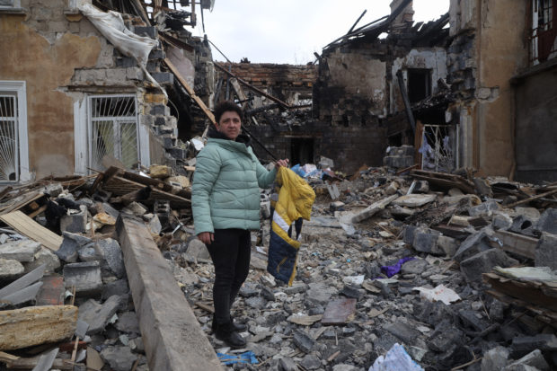 A woman holds a jacket as she examines ruins of a building where she was living before it was destroyd by Russian shelling in Mykolaiv, a key city on the road to Odessa, Ukraine's biggest port on March 27, 2022. - After some terrible weeks in which the Russian army has tried in vain to blow up this strategic city, the threat in the last few days seems to have eased a bit. Over the weekend, the air raid sirens were no longer disturbing locals in Mykolaiv, who were increasingly venturing out on the streets. Most barely hurry when they hear them. (Photo by Oleksandr GIMANOV / AFP)