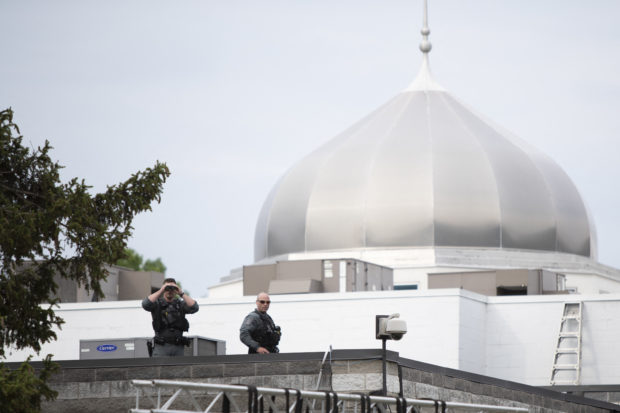 Police officers stand on the roof of the London Muslim Mosque during as Canada's Prime Minister Justin Trudeau attends vigil for the victims of the deadly vehicle attack on five members of the Canadian Muslim community in London, Ontario, Canada, June 8, 2021. - Canadian Prime Minister Justin Trudeau on Tuesday labeled as a "terrorist attack" the killing of four members of a Muslim family, who were run down by a man driving a pick-up truck. "This killing was no accident. This was a terrorist attack, motivated by hatred, in the heart of one of our communities," Trudeau said during a speech at the House of Commons. The suspect, identified as Nathaniel Veltman, 20, was arrested shortly after the June 6 attack, has been charged with four counts of first-degree murder and one count of attempted murder. (Photo by Nicole OSBORNE / AFP)