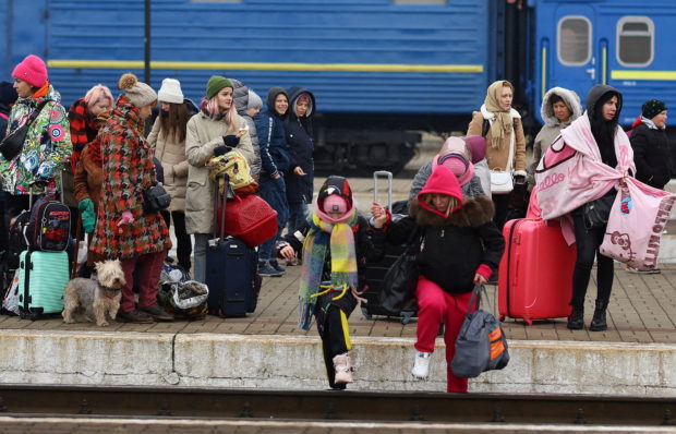 Refugees crossing the rail tracks as they try to reach trains to Poland following Russia’s invasion of Ukraine at the main train station in Lviv, Ukraine, March 4, 2022.   REUTERS/Kai Pfaffenbach