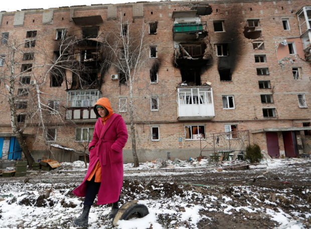 A woman walks in front of a residential building which was damaged during Ukraine-Russia conflict in the separatist-controlled town of Volnovakha in the Donetsk region, Ukraine March 11, 2022. REUTERS/Alexander Ermochenko