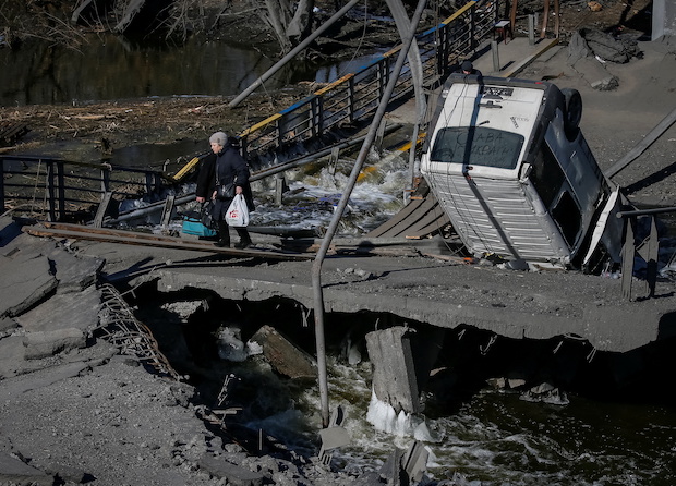 Woman crossing a destroyed bridge in Ukraine. STORY: Russia strikes military base near Polish border – Ukraine