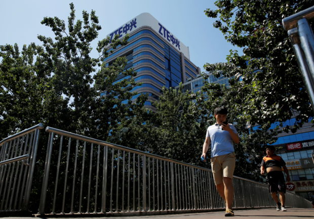 FILE PHOTO: People walk past a building of China's ZTE Corp in Beijing, China, August 29, 2018.  REUTERS/Thomas Peter/File Photo