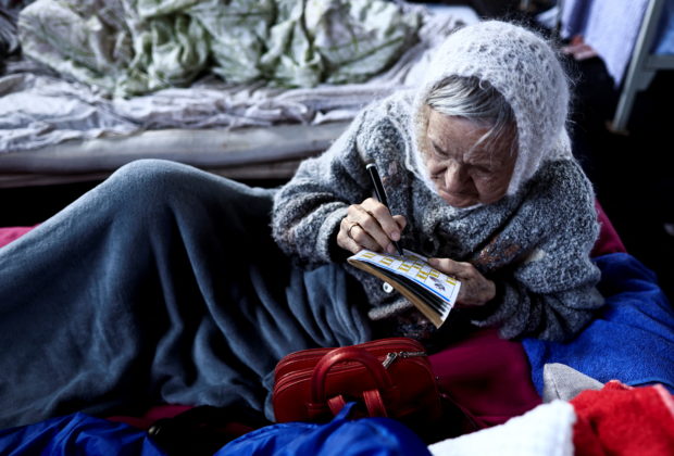 Svitlana Toryanik, 81, from Kharkiv who fled Russia's ongoing invasion of Ukraine, plays crosswords as she lies down at the gym turned-shelter in Lviv, Ukraine March 19, 2022. REUTERS/Zohra Bensemra