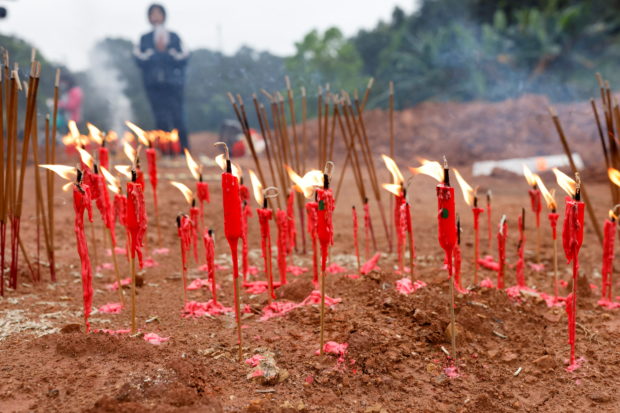 People burn candles and incense sticks during a Buddhist ceremony in honor of the victims in a field close to the entrance of Simen village, near the site where a China Eastern Airlines Boeing 737-800 plane flying from Kunming to Guangzhou crashed, in Wuzhou, Guangxi Zhuang Autonomous Region, China March 22, 2022. REUTERS/Carlos Garcia Rawlins