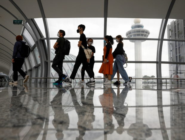 FILE PHOTO: People pass the control tower of Singapore's Changi Airport, Singapore January 18, 2021. REUTERS/Edgar Su/File Photo