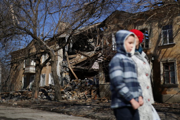 Natalia (32) and her son Micha (9) walk past a damaged building after a military strike hit their neighborhood, as Russia's invasion of Ukraine continues, in Mykolaiv, Ukraine, March 24, 2022. REUTERS/Nacho Doce