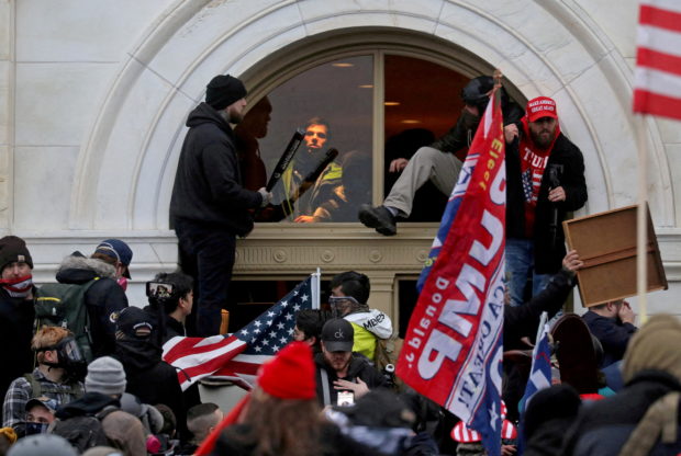 FILE PHOTO: A mob of supporters of then-U.S. President Donald Trump climb through a window they broke as they storm the U.S. Capitol Building in Washington, U.S., January 6, 2021. REUTERS/Leah Millis/File Photo