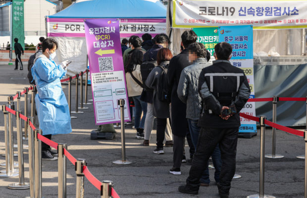 People stand in line to take coronavirus tests at a makeshift testing station in front of Seoul Station