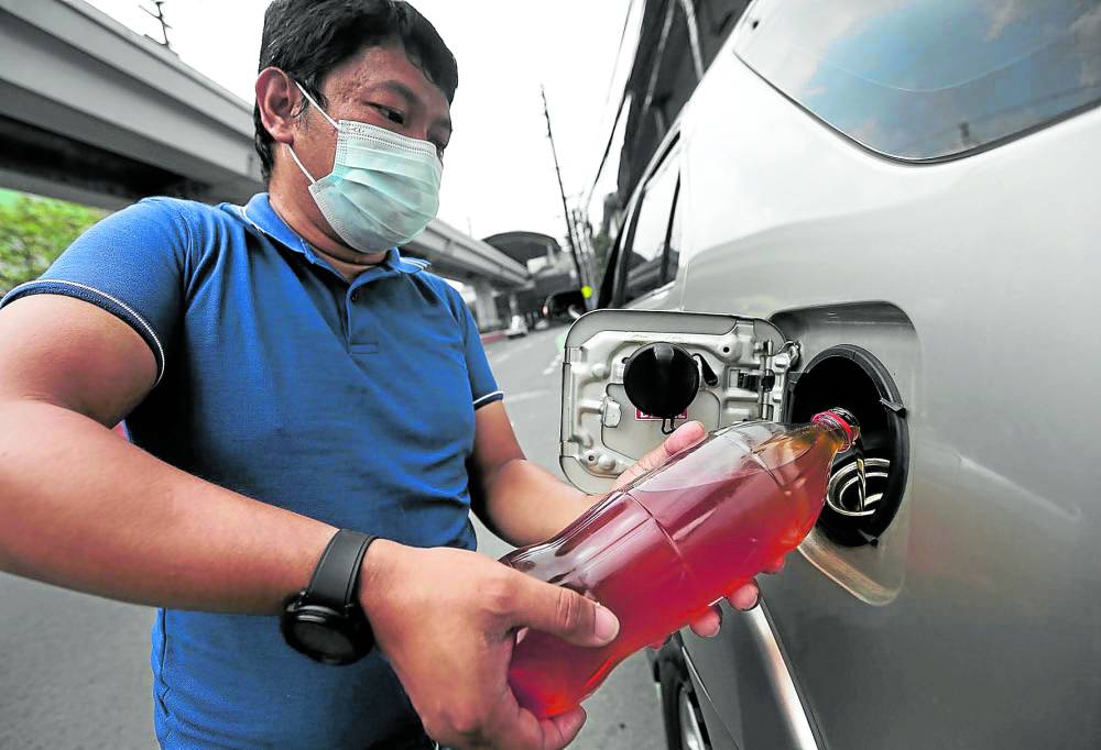 Brisenio, an engineer, loads a bottle of cooking oil into his car 