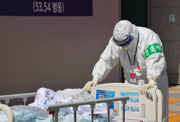 A medical worker moves a COVID-19 patient at a Seoul hospital on Tuesday