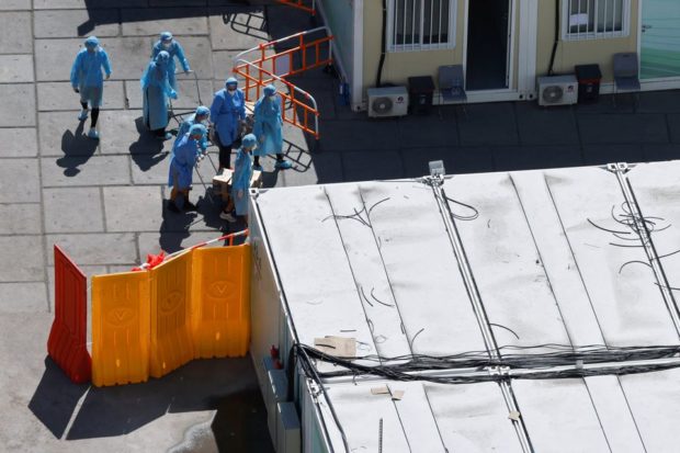 Workers wear personal protective equipment (PPE) at a coronavirus disease (COVID-19) isolation facility in Tsing Yi