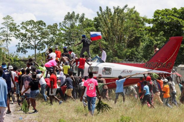 Demonstrators stand on top of a plane belonging to U.S. missionary group Agape Flights