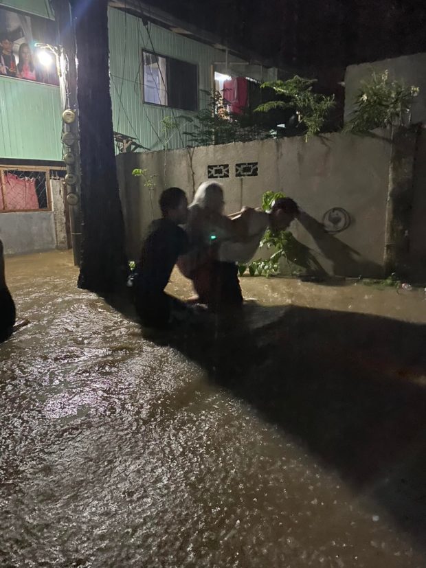 Rescuers help to carry to safety an elderly resident in Barangay Suarez, Iligan City amid rising floodwaters on Sunday evening