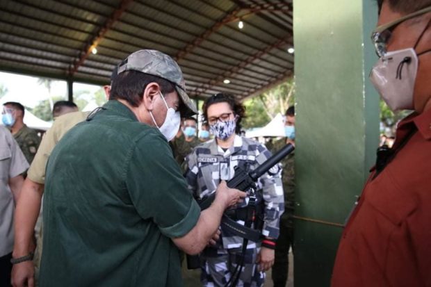 Major Zeerah Blanche Lucrecia in camouflage uniform with President Rodrigo Duterte who is holding a gun.