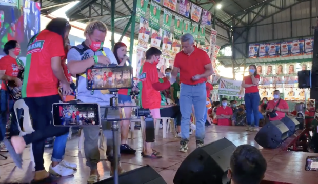 Cavite Governor Jonvic Remulla hands out cash to participants in a song and dance showdown during the sortie of Uniteam's Ferdinand "Bongbong" Marcos Jr. and Sara Duterte-Carpio. Screengrab Twitter / Neil Arwin Mercado 