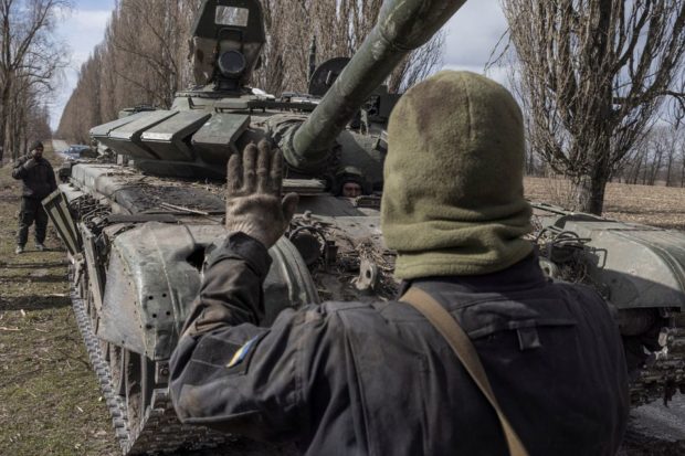 Ukranian serviceman walks past a Russian tank